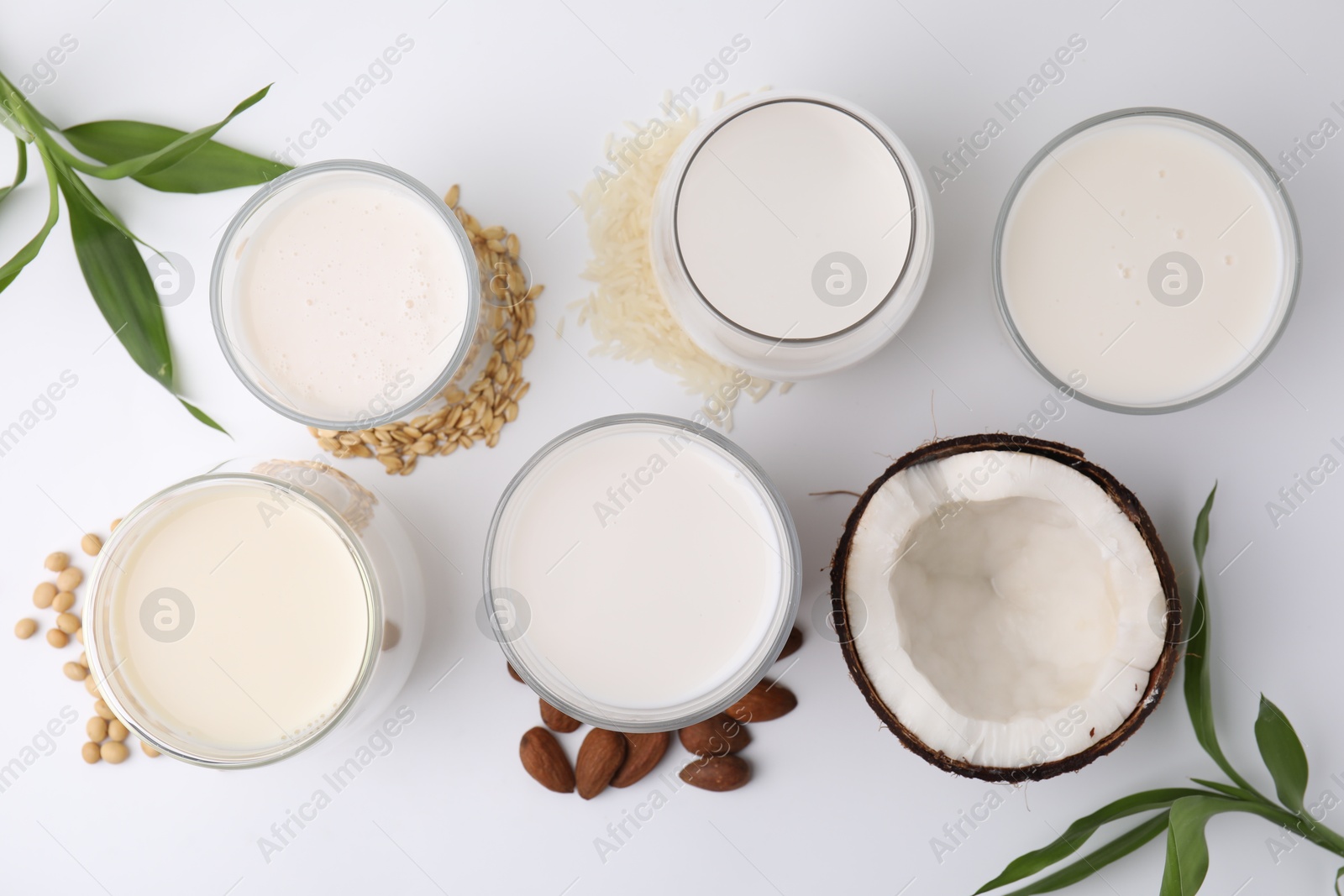 Photo of Different types of vegan milk and ingredients on white table, flat lay