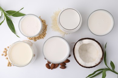 Photo of Different types of vegan milk and ingredients on white table, flat lay