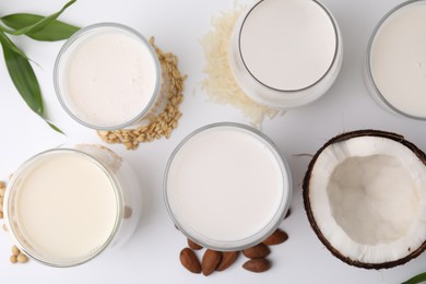 Photo of Different types of vegan milk and ingredients on white table, flat lay