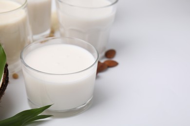 Photo of Different types of vegan milk and ingredients on white table, closeup