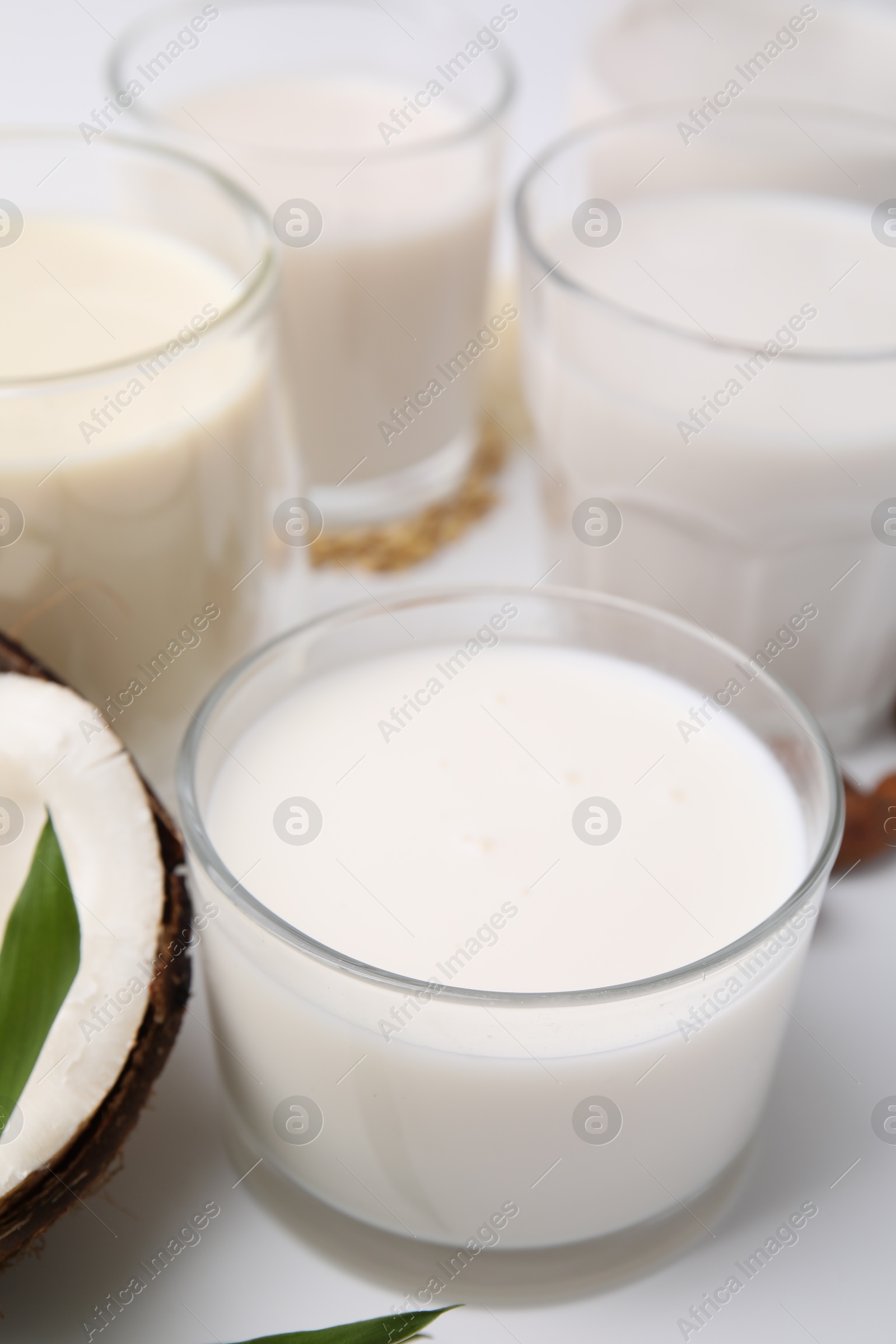 Photo of Different types of vegan milk on white table, closeup