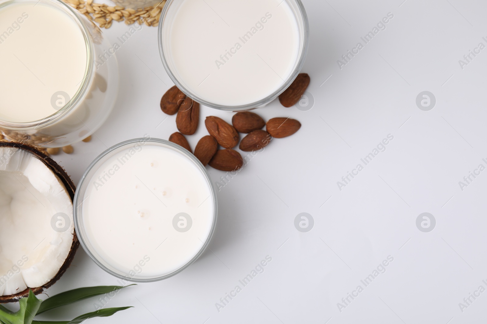 Photo of Different types of vegan milk and ingredients on white table, flat lay. Space for text