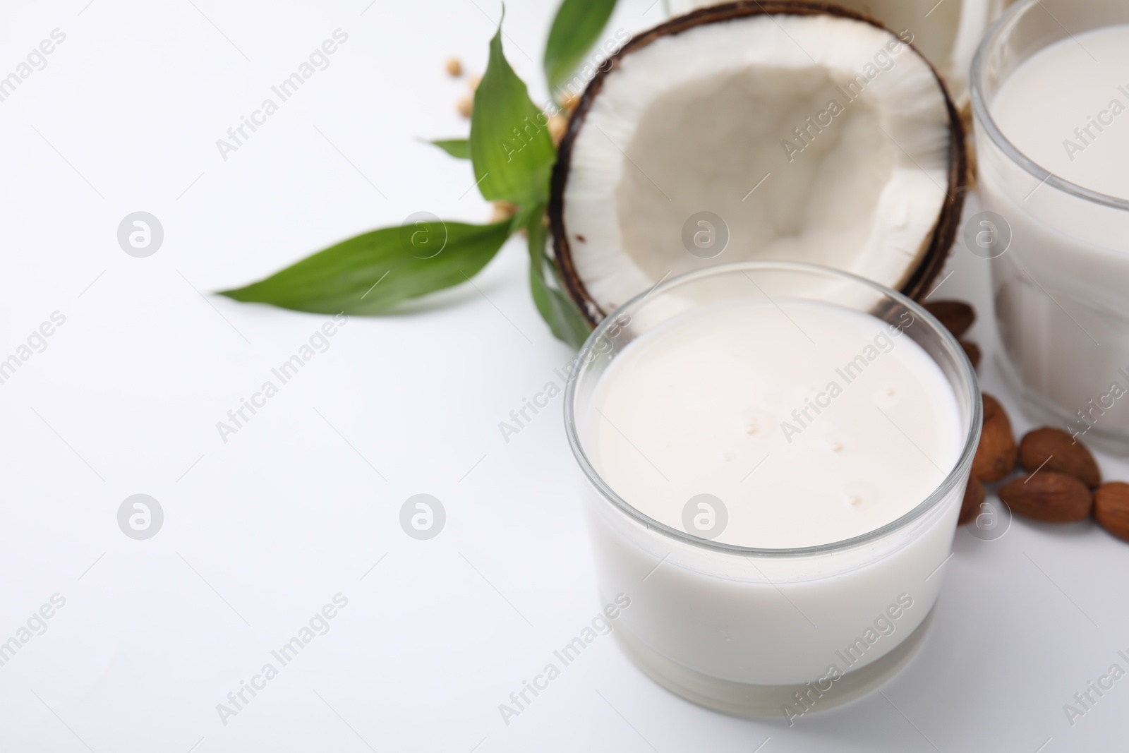 Photo of Different types of vegan milk and ingredients on white table