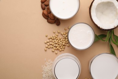 Photo of Different types of vegan milk and ingredients on beige table, flat lay. Space for text