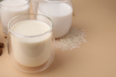 Photo of Different types of vegan milk and ingredients on beige table, closeup