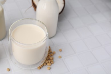 Photo of Different types of vegan milk and ingredients on white tiled table, closeup. Space for text