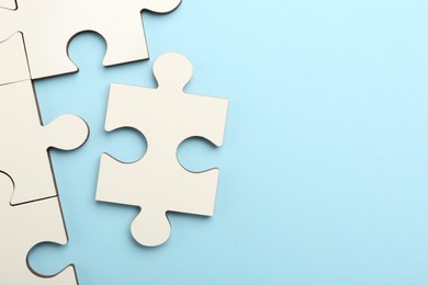 White puzzle pieces on light blue background, top view. Space for text