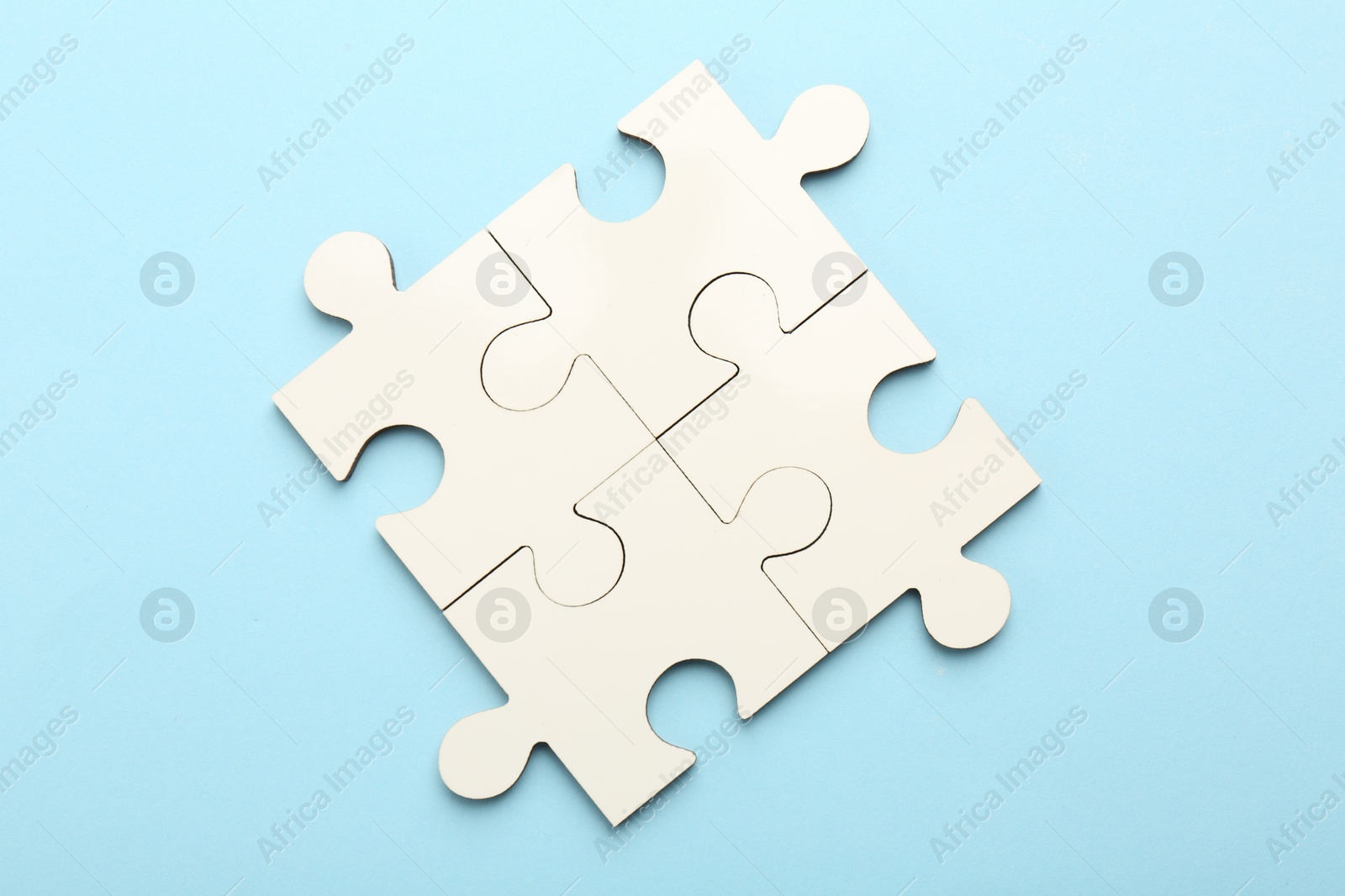 Photo of White puzzle pieces on light blue background, top view