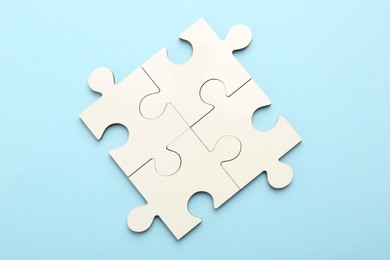 White puzzle pieces on light blue background, top view