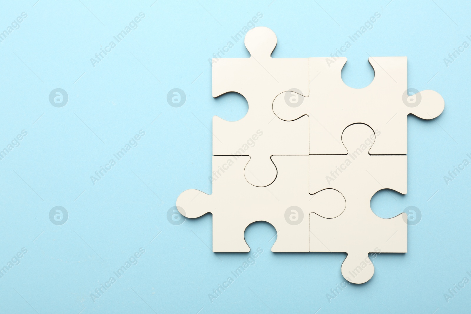 Photo of White puzzle pieces on light blue background, top view. Space for text