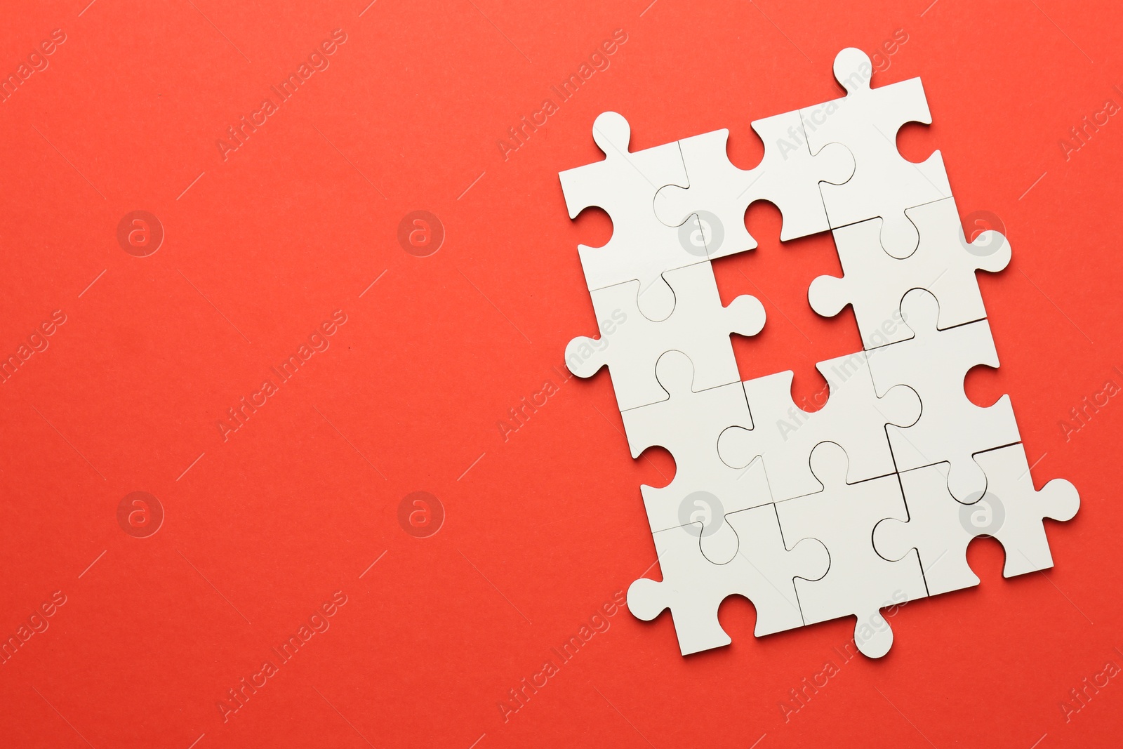 Photo of White puzzle pieces on red background, top view. Space for text