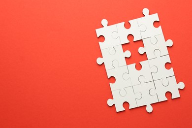 White puzzle pieces on red background, top view. Space for text