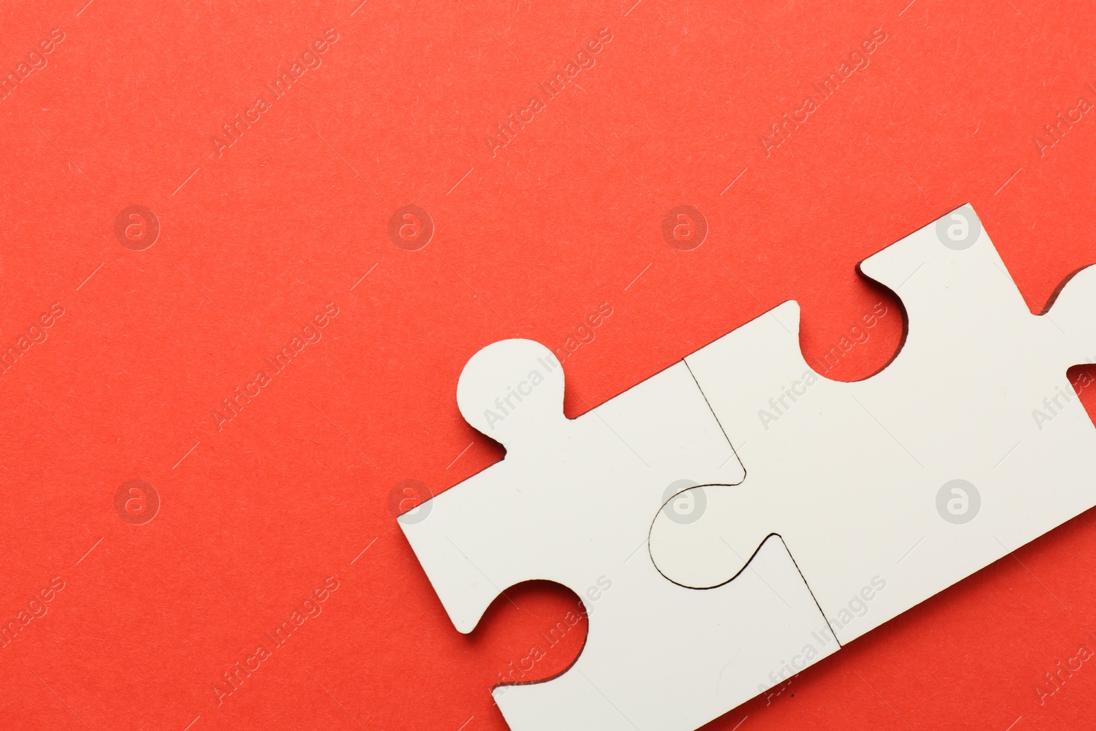 Photo of White puzzle pieces on red background, top view. Space for text