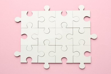 White puzzle pieces on pink background, top view