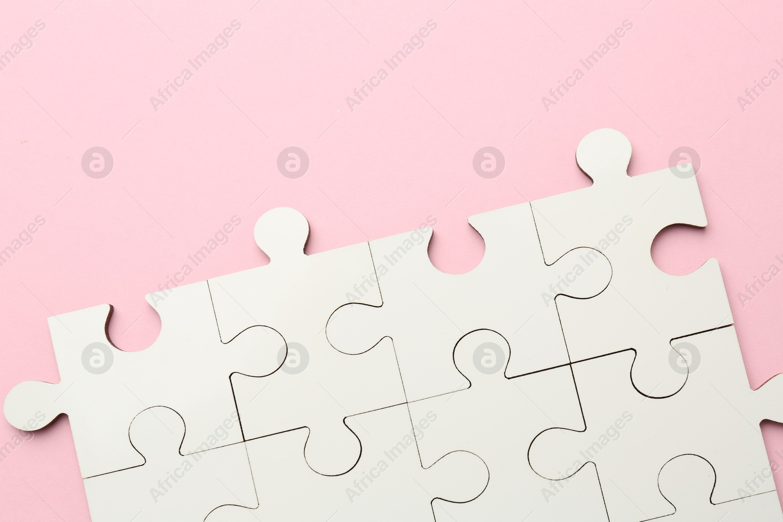 Photo of White puzzle pieces on pink background, top view