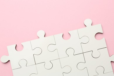 White puzzle pieces on pink background, top view