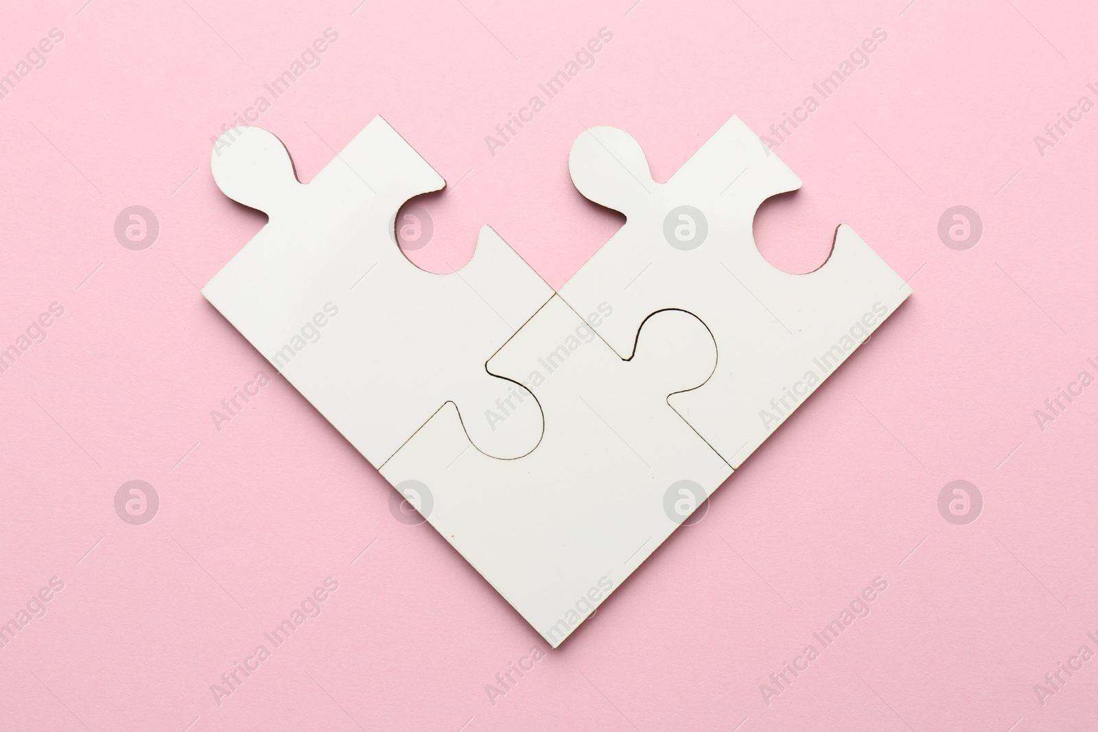 Photo of White puzzle pieces on pink background, top view