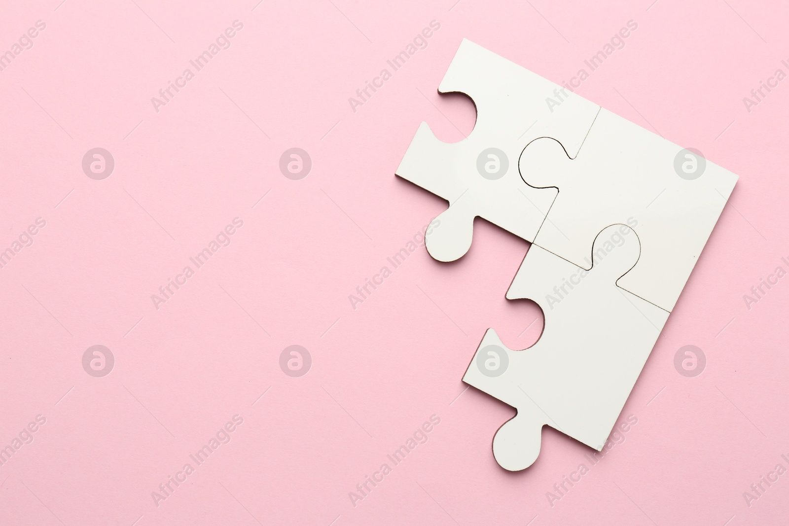 Photo of White puzzle pieces on pink background, top view. Space for text