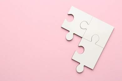 White puzzle pieces on pink background, top view. Space for text