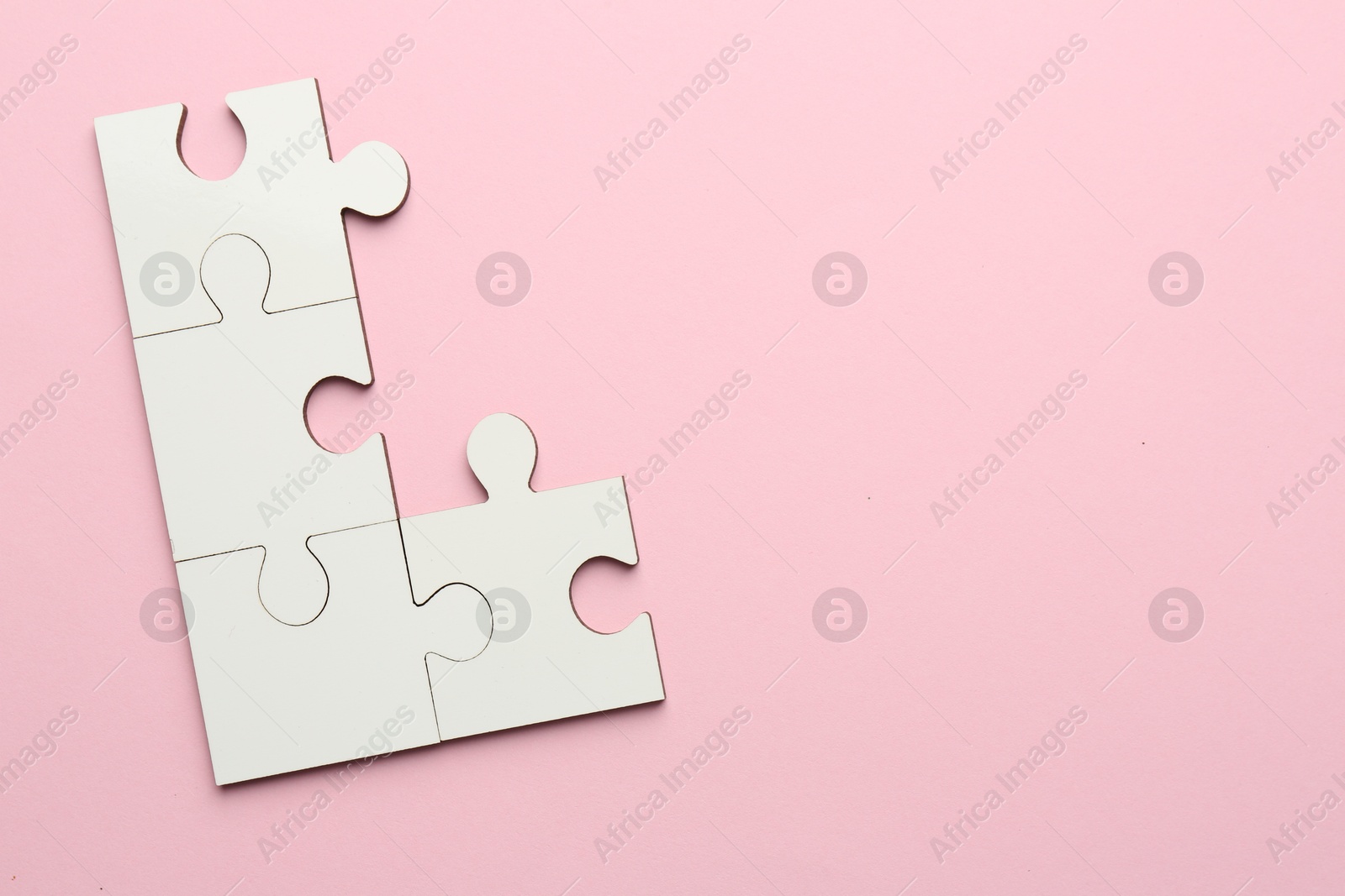 Photo of White puzzle pieces on pink background, top view. Space for text