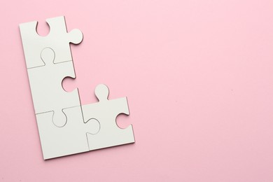 Photo of White puzzle pieces on pink background, top view. Space for text