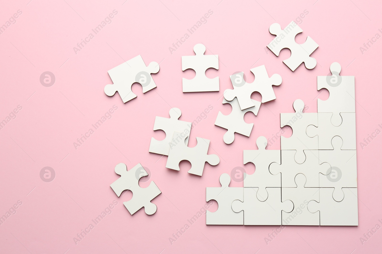 Photo of White puzzle pieces on pink background, top view