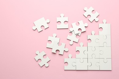 White puzzle pieces on pink background, top view