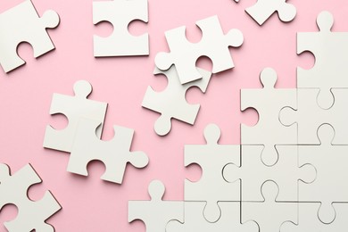 Photo of White puzzle pieces on pink background, top view