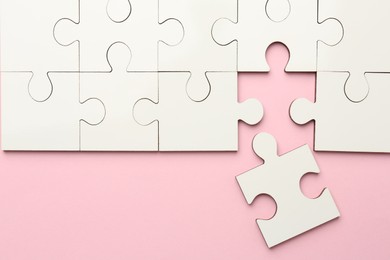 Photo of White puzzle pieces on pink background, top view