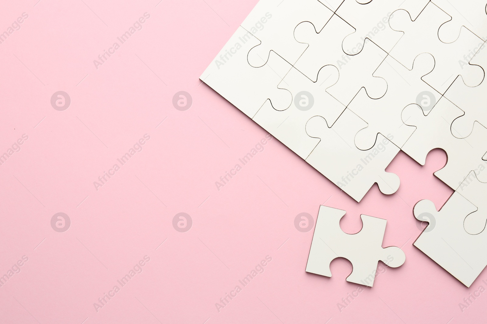 Photo of White puzzle pieces on pink background, top view. Space for text