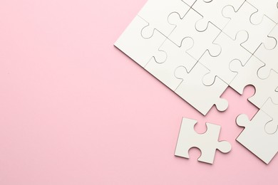 White puzzle pieces on pink background, top view. Space for text