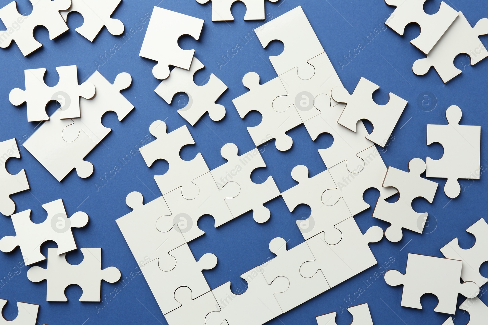 Photo of White puzzle pieces on blue background, top view