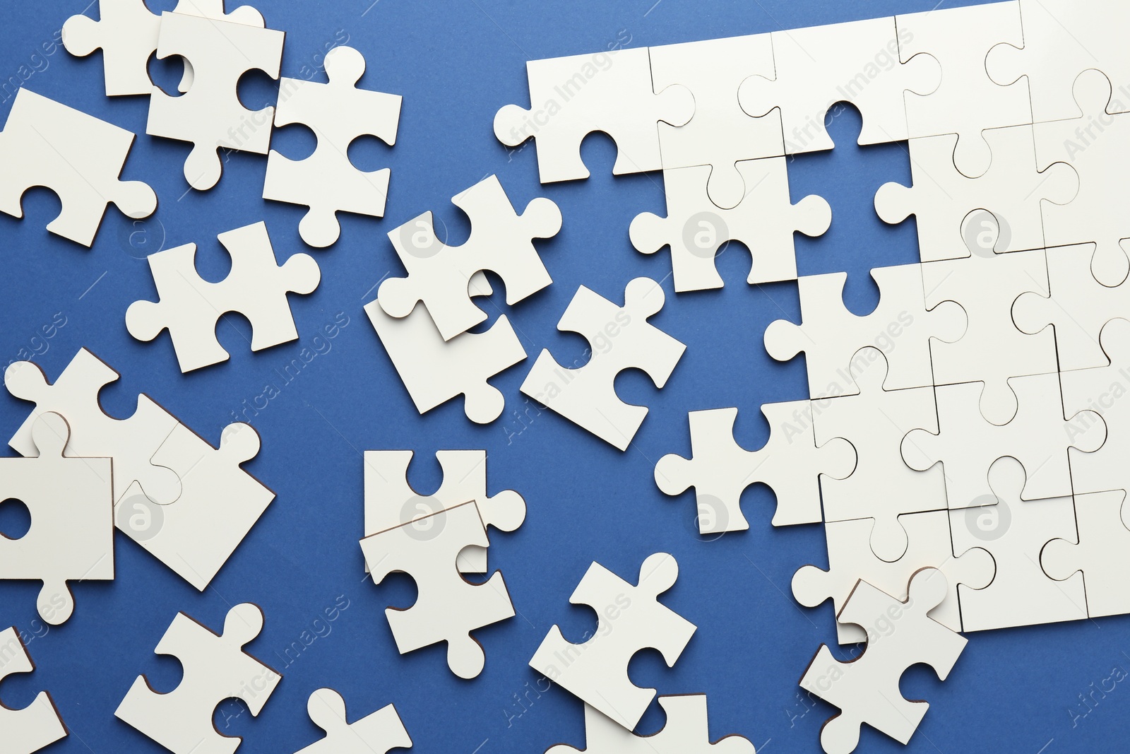 Photo of White puzzle pieces on blue background, top view