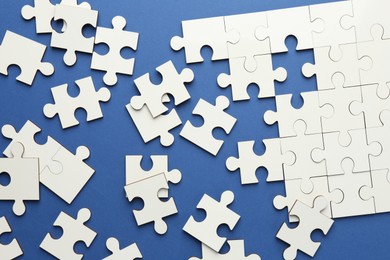 White puzzle pieces on blue background, top view