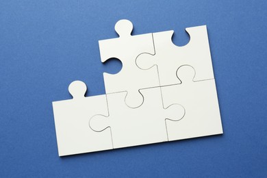 White puzzle pieces on blue background, top view