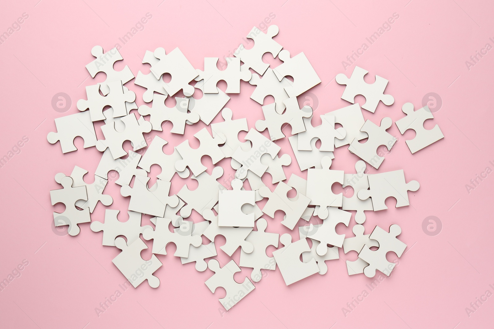 Photo of White puzzle pieces on pink background, top view