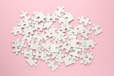 White puzzle pieces on pink background, top view