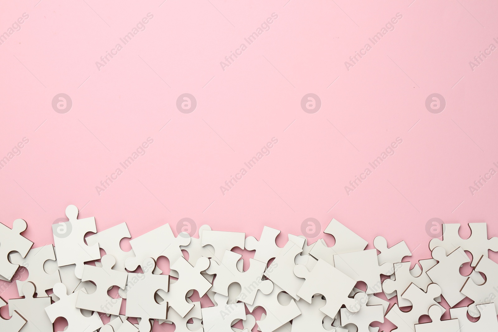 Photo of White puzzle pieces on pink background, top view. Space for text