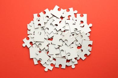 Pile of white puzzle pieces on red background, top view