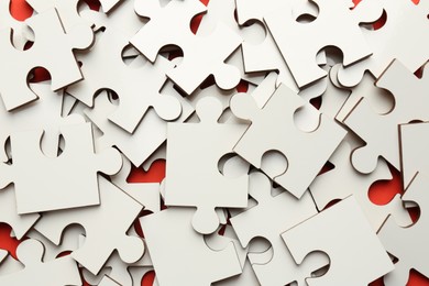 Pile of white puzzle pieces on red background, closeup