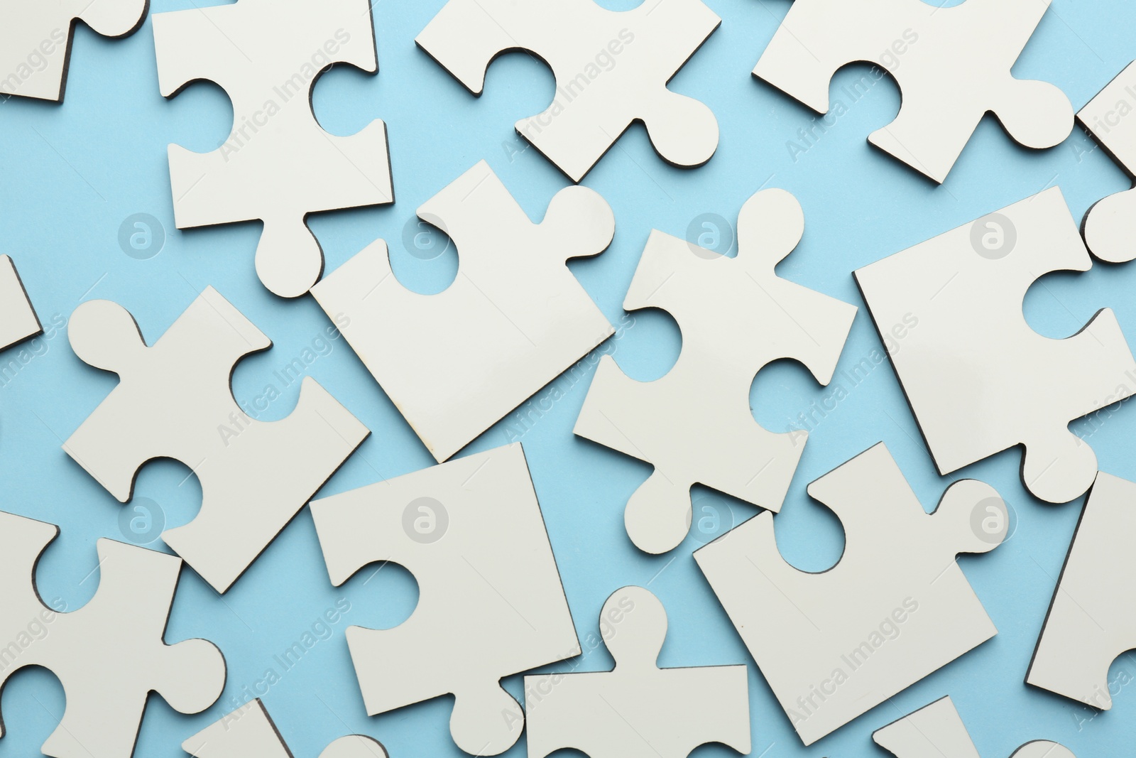 Photo of White puzzle pieces on light blue background, top view