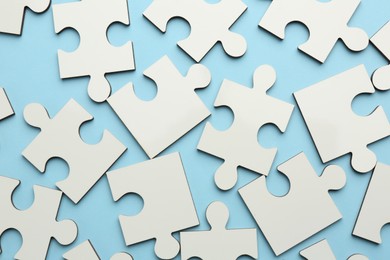 Photo of White puzzle pieces on light blue background, top view