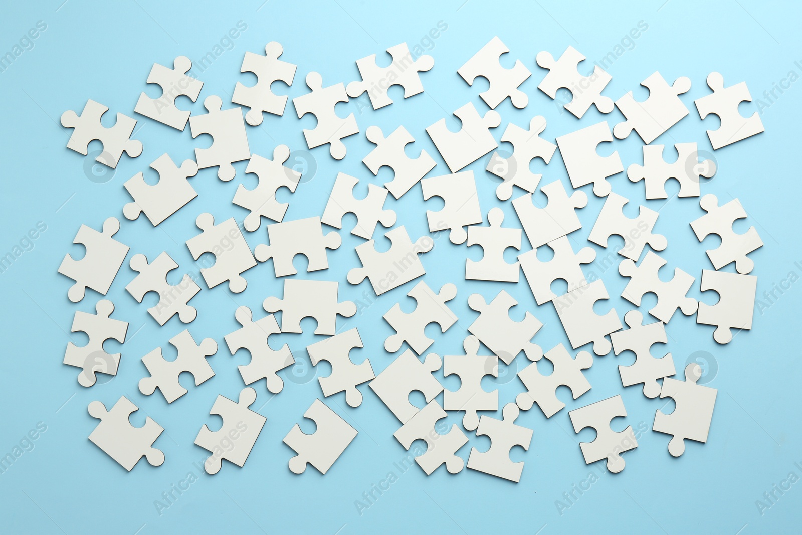 Photo of White puzzle pieces on light blue background, top view