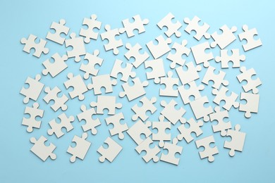 Photo of White puzzle pieces on light blue background, top view