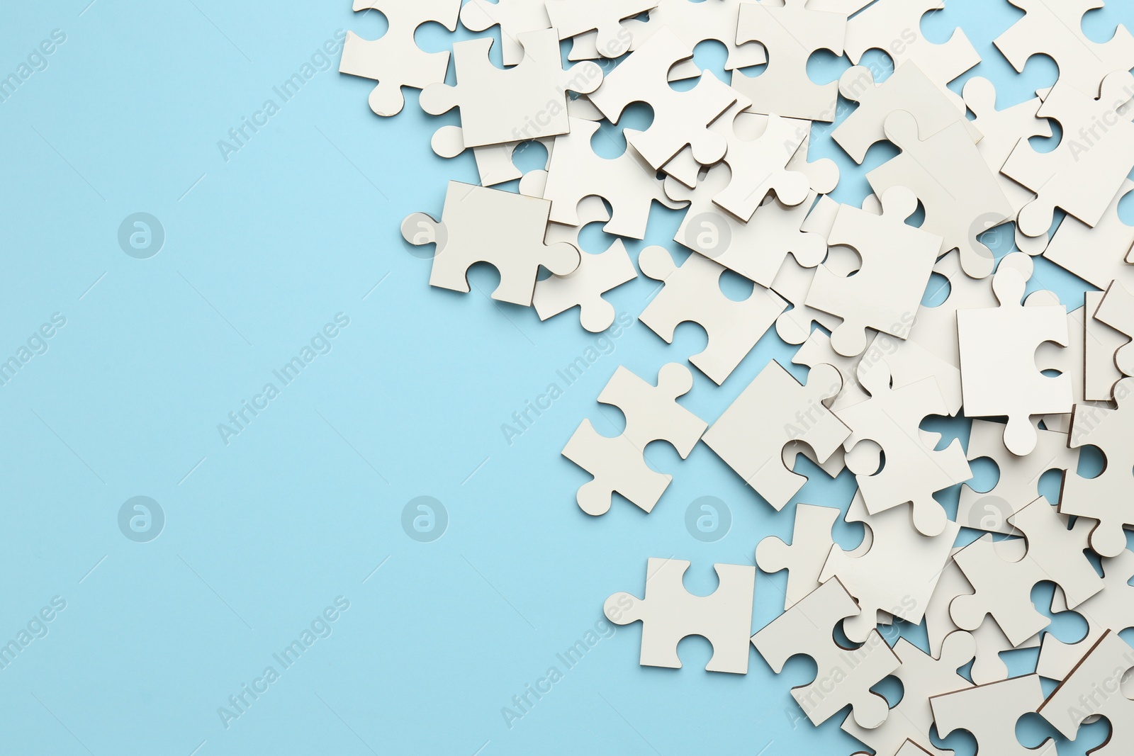 Photo of White puzzle pieces on light blue background, top view. Space for text