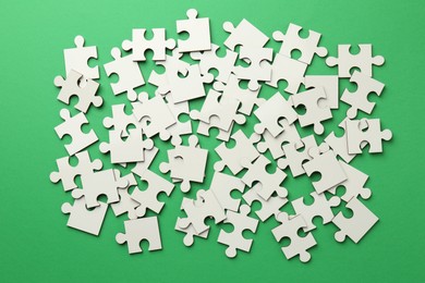 Photo of White puzzle pieces on green background, top view