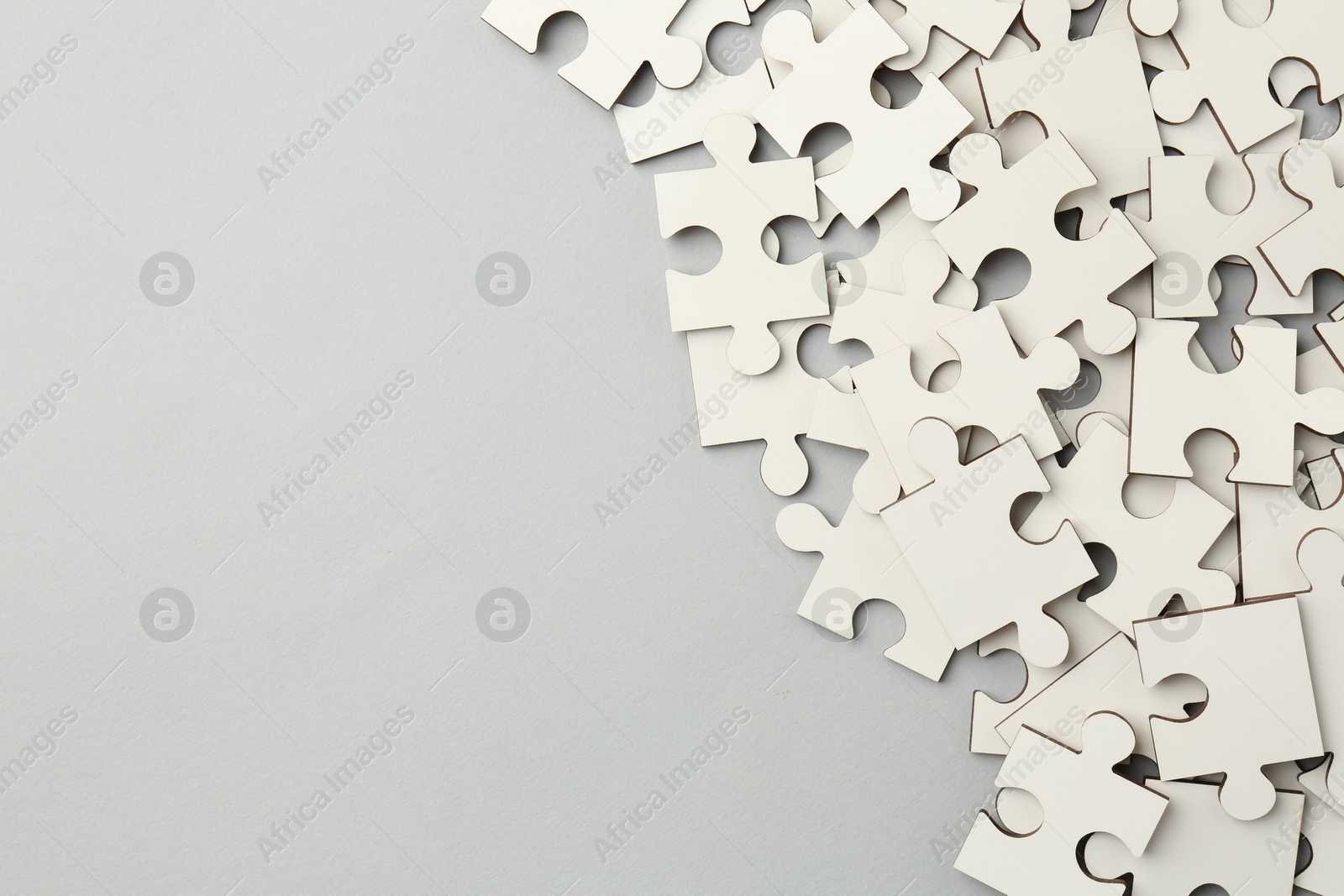 Photo of White puzzle pieces on grey background, top view. Space for text