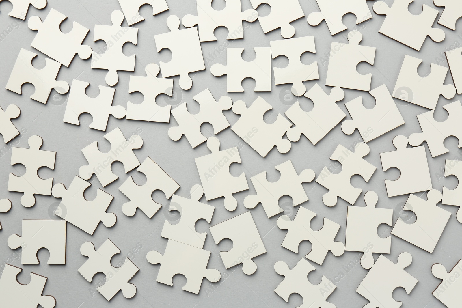 Photo of White puzzle pieces on grey background, top view