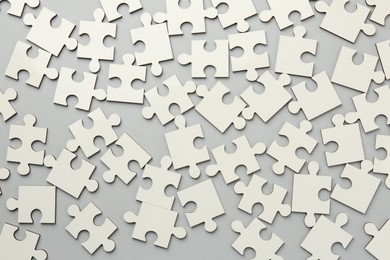 White puzzle pieces on grey background, top view