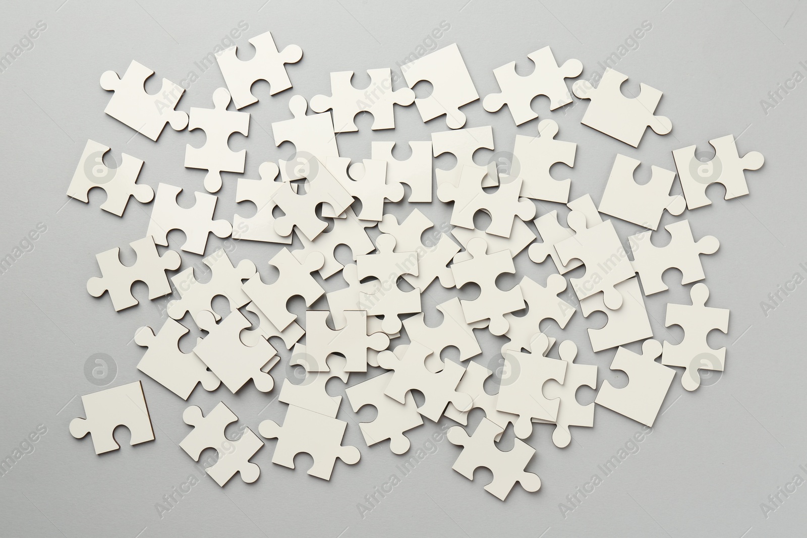 Photo of White puzzle pieces on grey background, top view